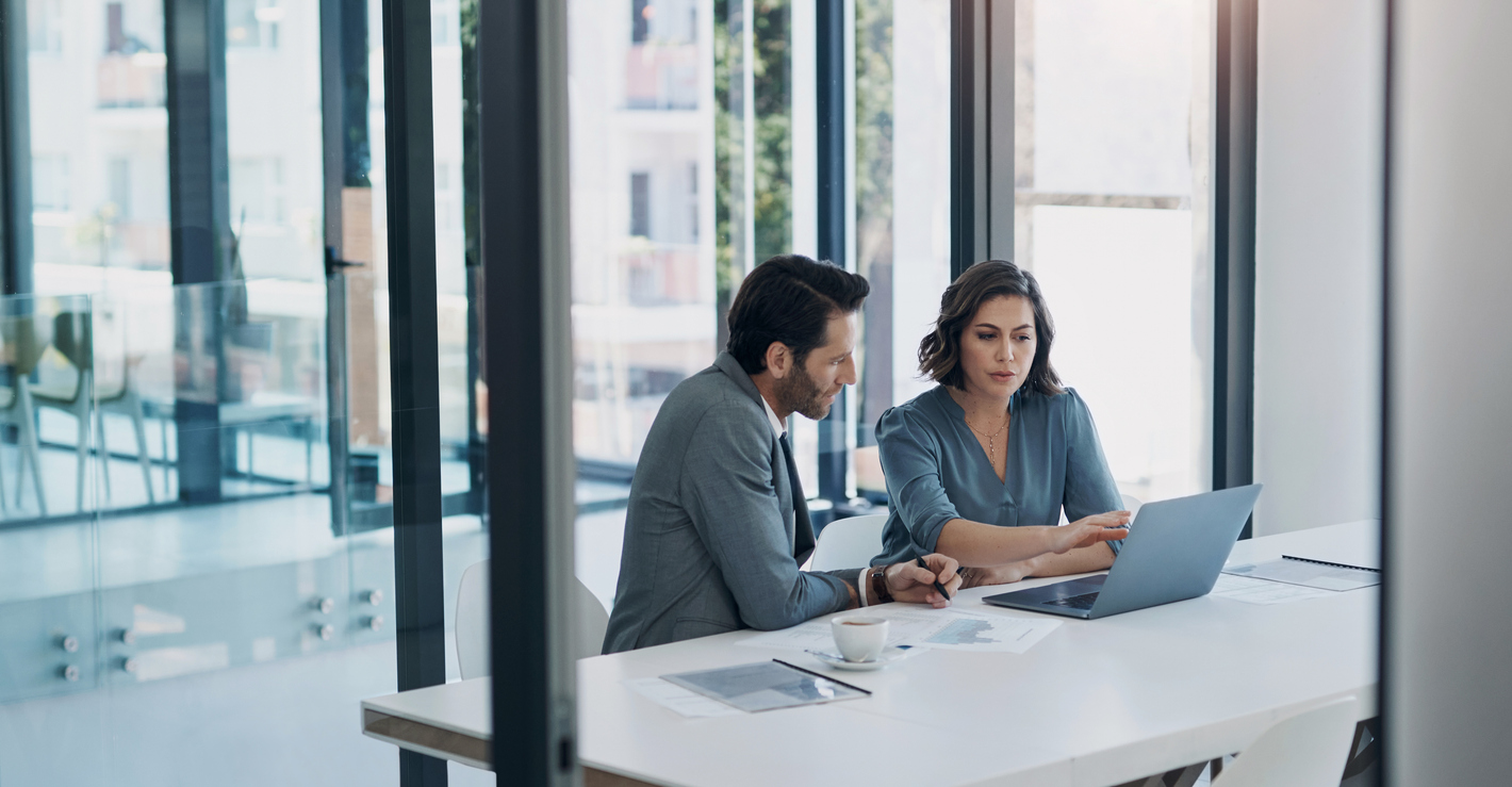 Business Man, Woman And Laptop In Discussion In Team, Brainstorming Or Proposal For B2b Collaboration. People, Computer Or Meeting With Paperwork For Financial Strategy, Idea Or Negotiation In Office